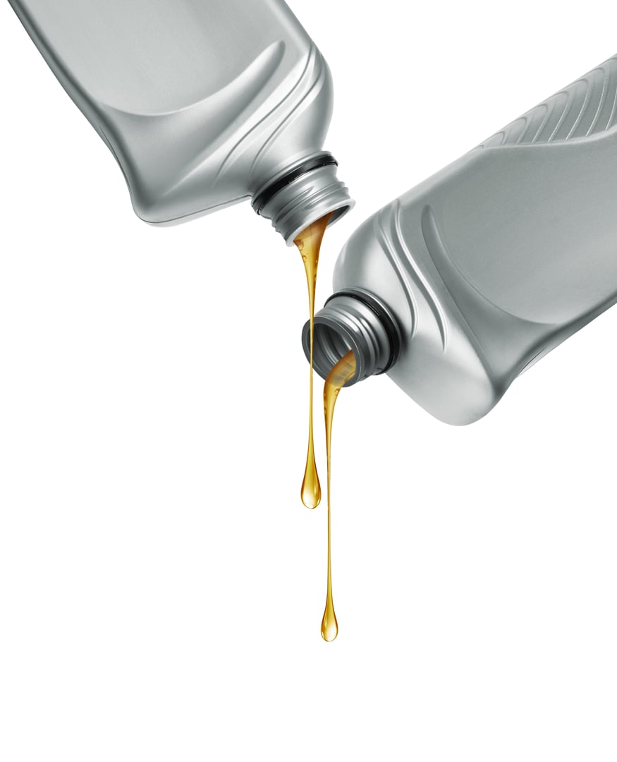 Stretched drops of oily liquid dripping from two gray plastic bottles